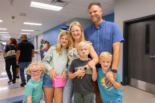 family smiling inside school building
